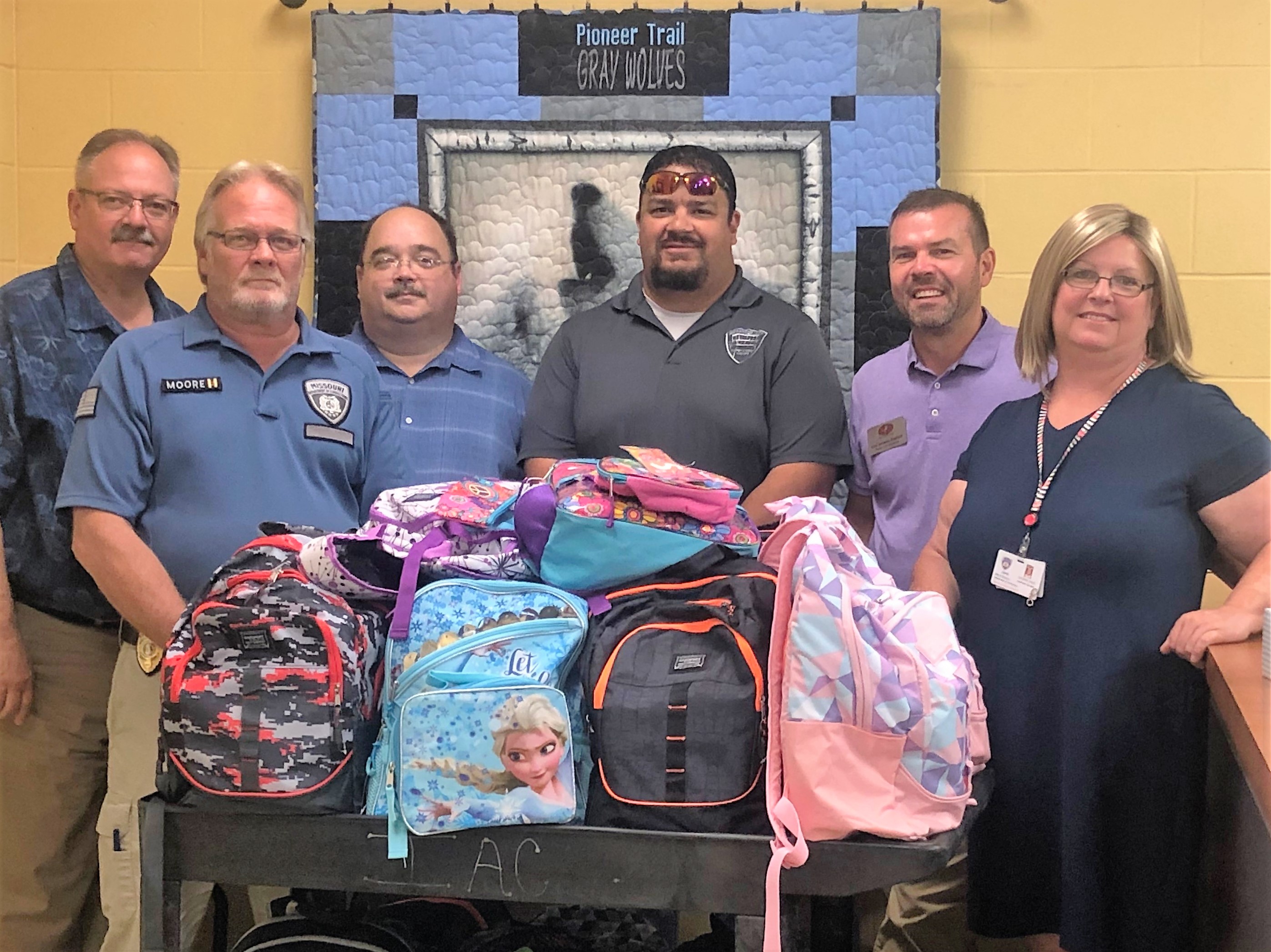 Staff pose with backpacks filled with school supplies for Missouri kids.