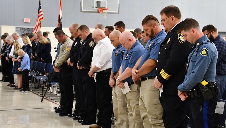 Officers bow their heads in prayer before the Public Safety Awards.