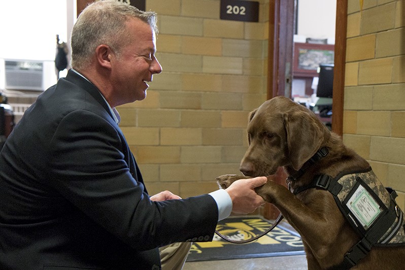 A disabled veteran shakes hands with his new service dog.