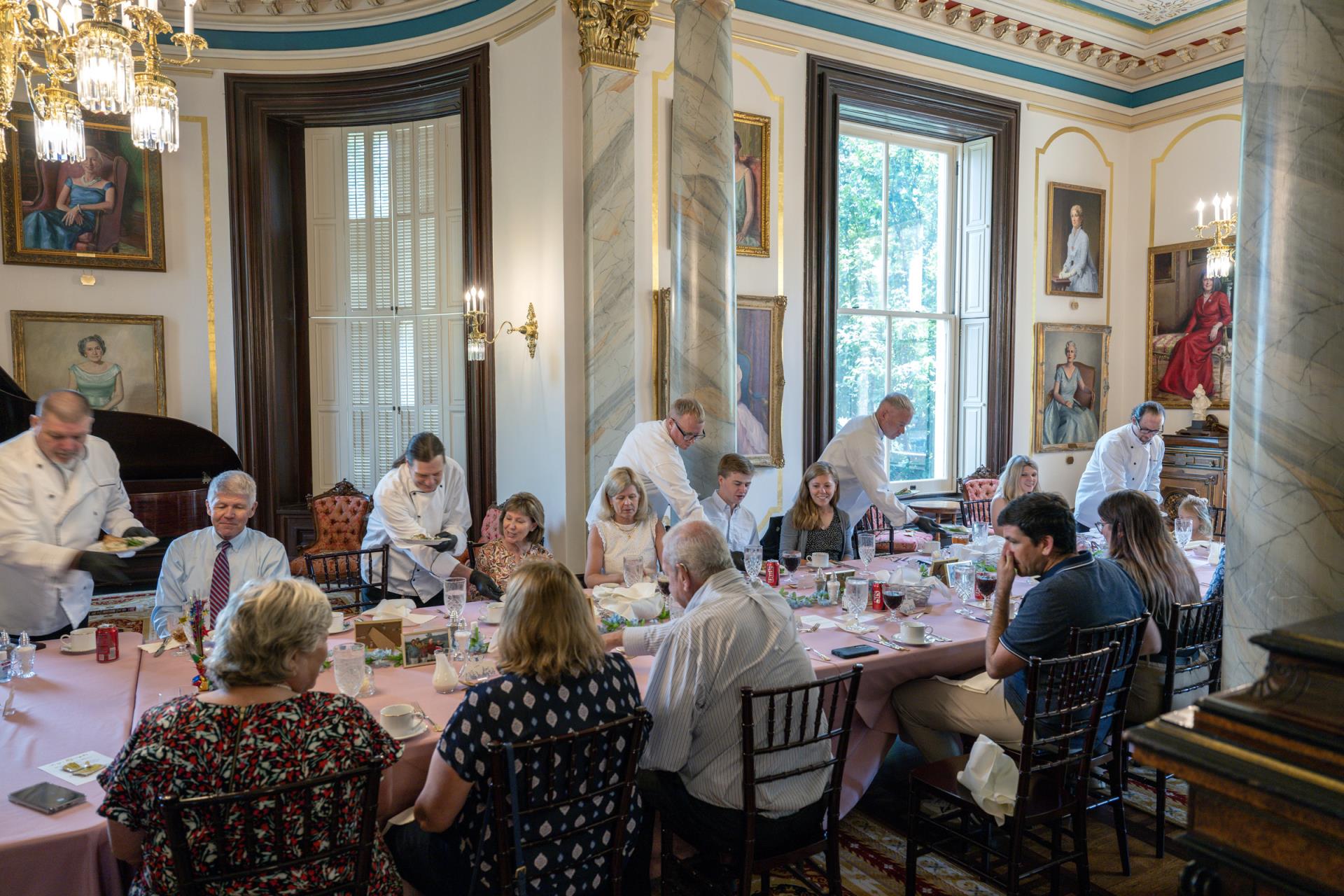 Work-release participants serve guests at the Governor's Mansion. The dining room is decorated with portraits of past Missouri first ladies.