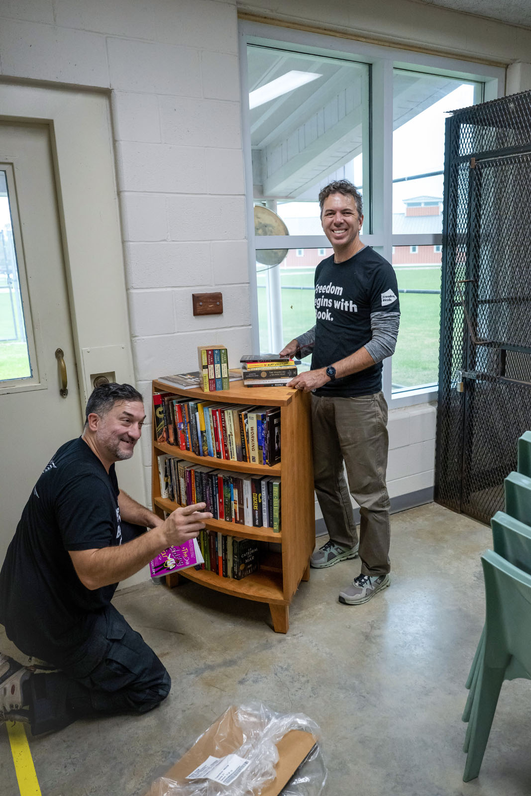 Freedom Reads workers smile as they stock a bookcase.