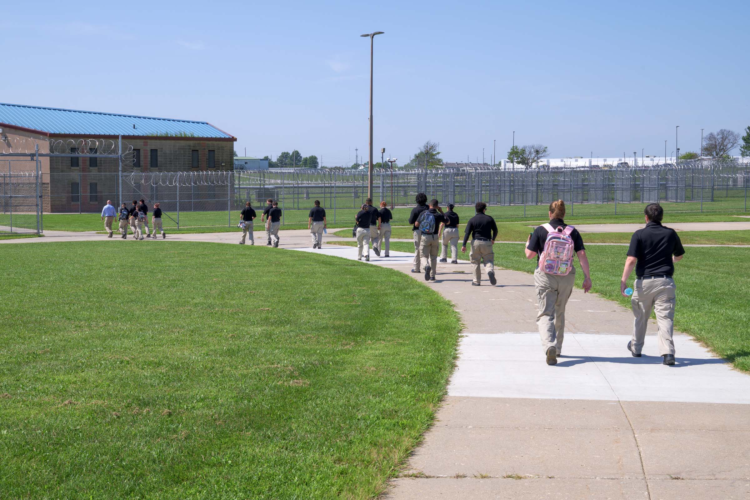A line of cadets walks along a path outside the AEC.