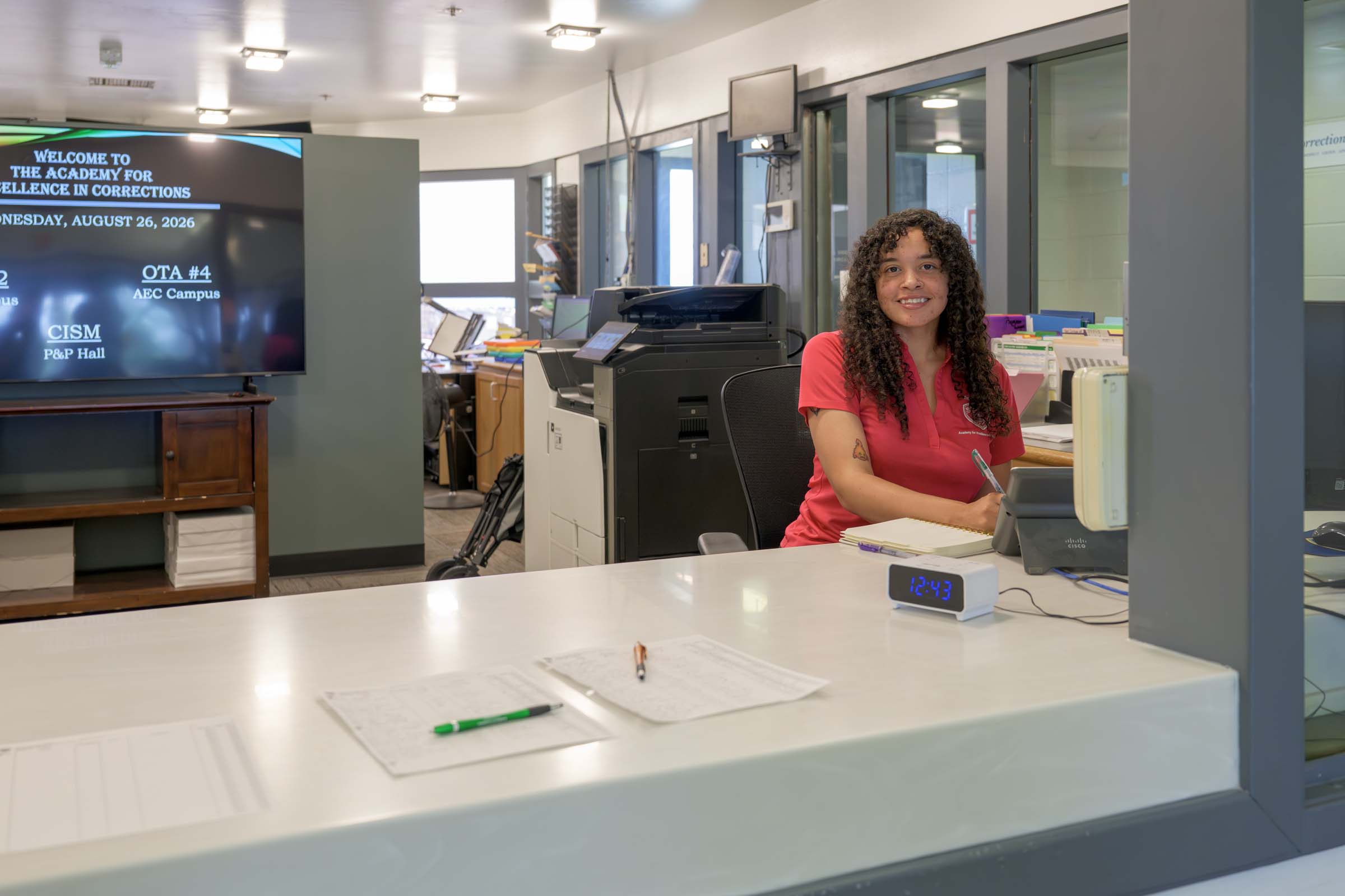 Markecia Wilson smiles from behind a desk at the AEC entryway.