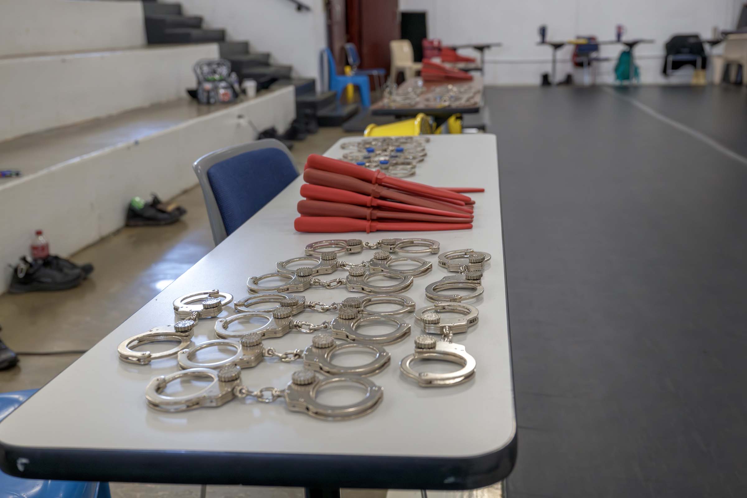 Handcuffs and rubber safety weapons for training await the next exercise on a nearby table.