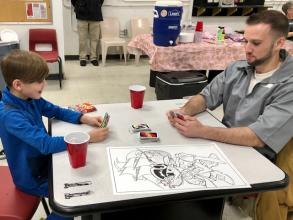 An offender plays an UNO card game with his young son at a visiting room table.