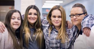 Four women with their arms around one another.
