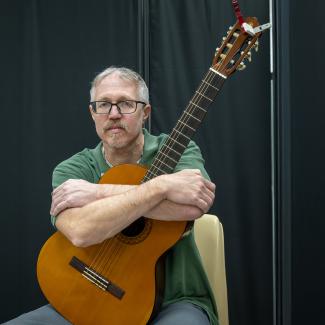 Singer-songwriter Jeremiah Johnson poses with his arms around his guitar