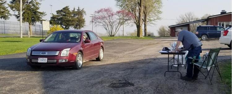 A car pulling up to a desk set up in a parking lot