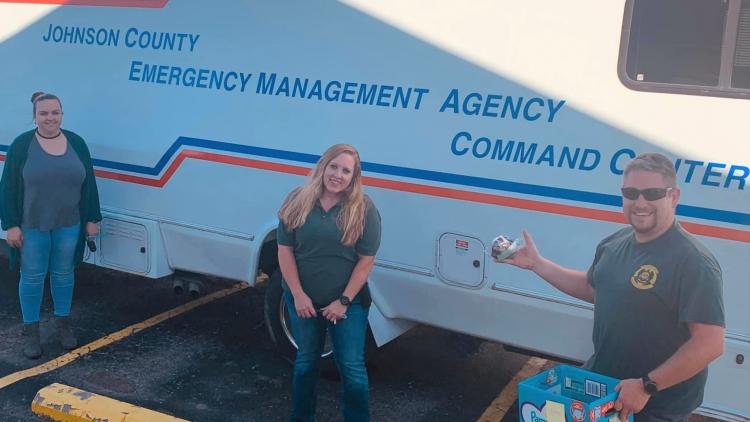 Three parole officers in front of an emergency management truck handing out snack bags