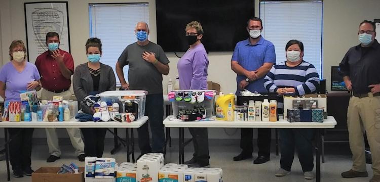 Eight staff members display the items they're donating to a women's shelter
