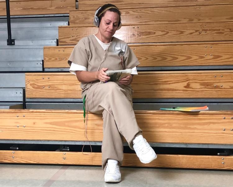 Female offender with computer tablet and headphones.