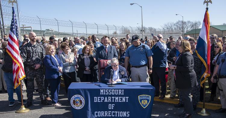 Governor Mike Parson signs a supplemental budget bill amid a huge crowd of corrections staff