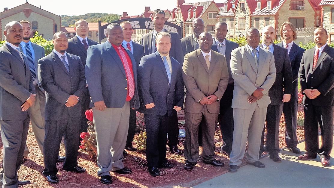 A group of a dozen men in suits in front of Algoa Correctional Center