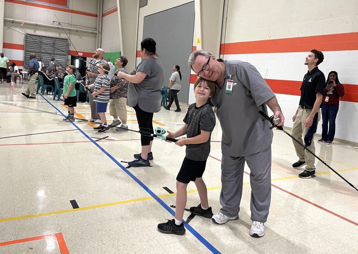 Dads and kids practice casting fishing reels at Southeast Correctional Center