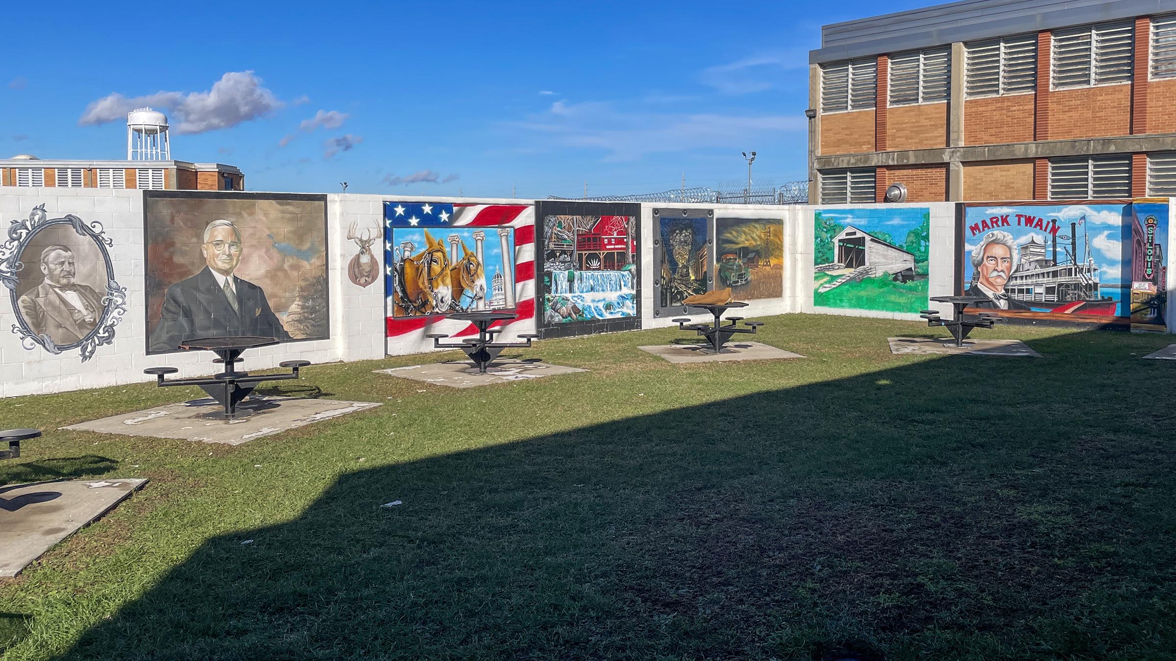 Wide shot of a series of colorful murals depicting historical scenes on a concrete wall