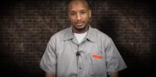 Man in a prison uniform looking at the camera