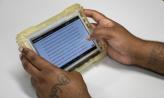 Two tattooed hands holding a JPay computer tablet.